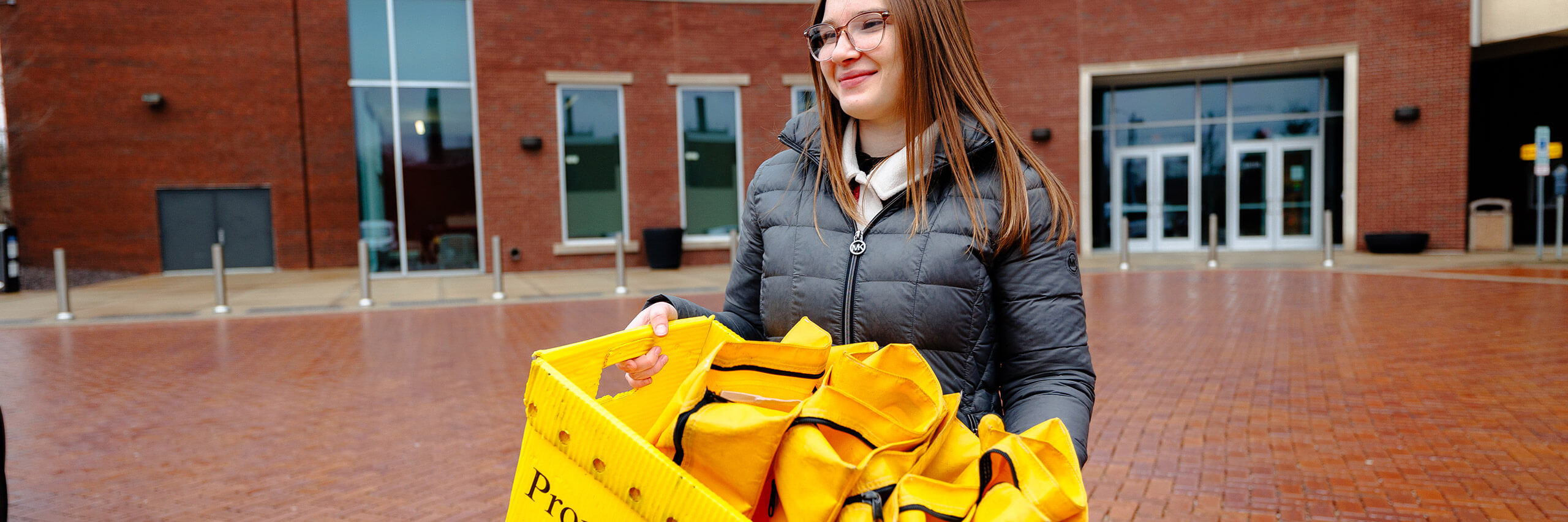 A mail service employee outside with a basket with mail